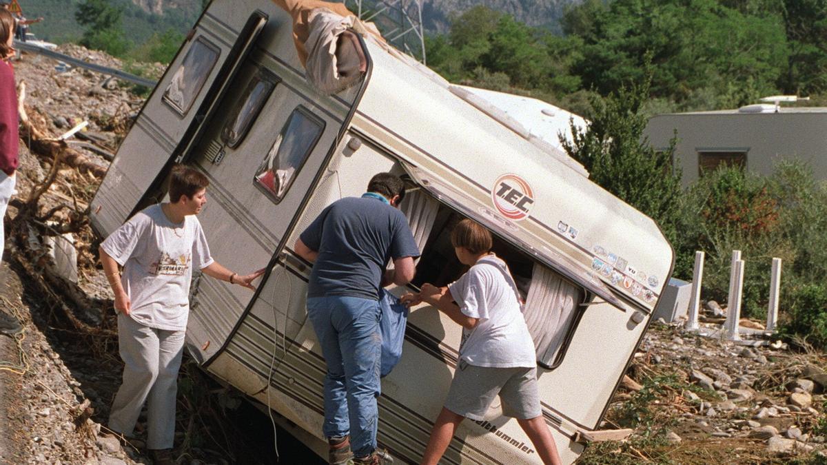 Una familia recupera sus enseres de una caravana arrollada por la avalancha de agua y piedras.