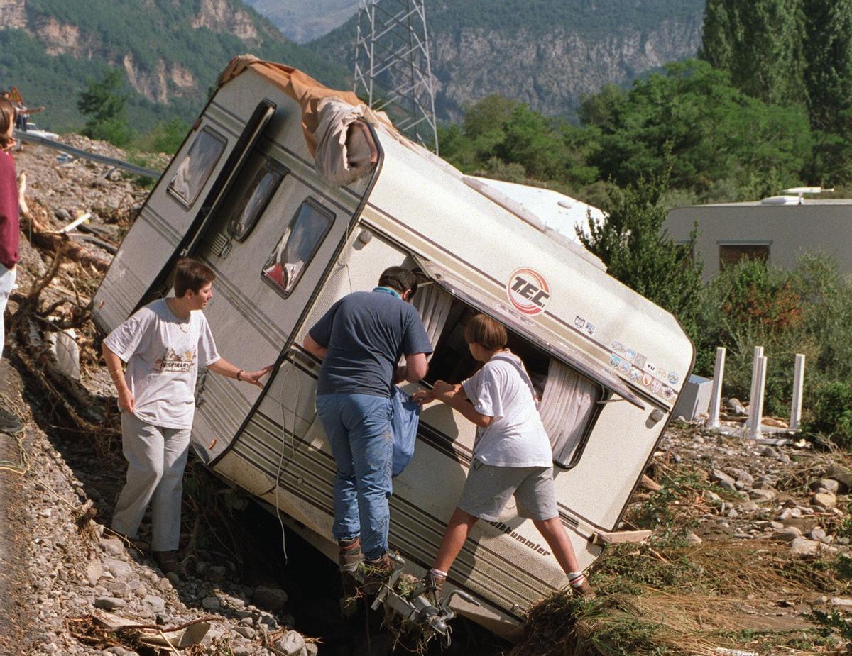 Una familia recupera sus enseres de una caravana arrollada por la avalancha de agua y piedras.