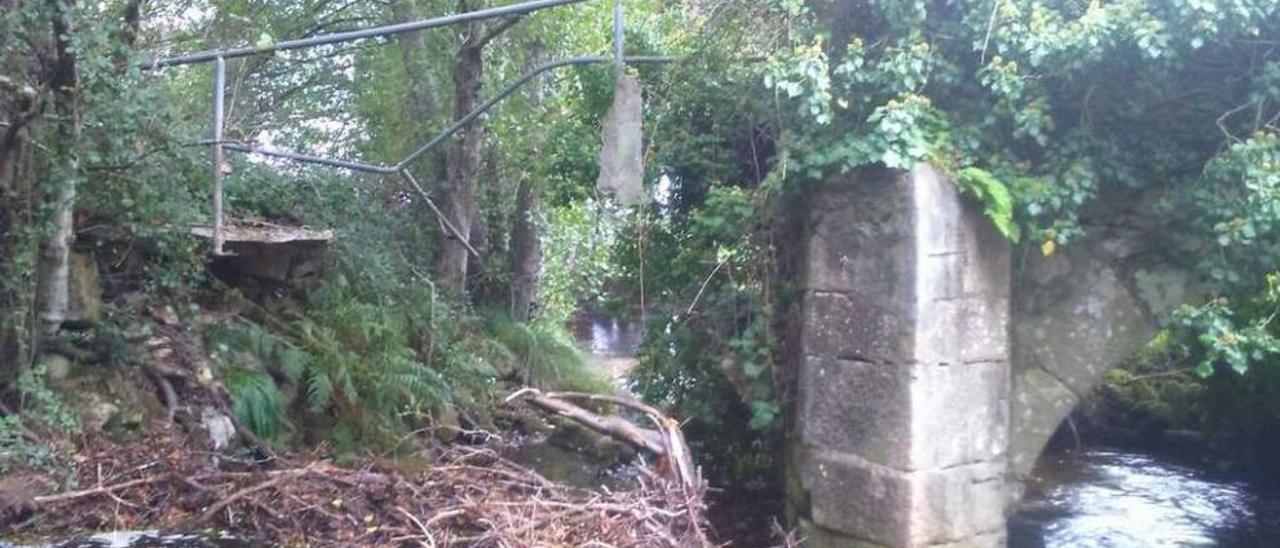 Una arcada se desplomó ya sobre el río, y la otra está cubierta por la maleza.