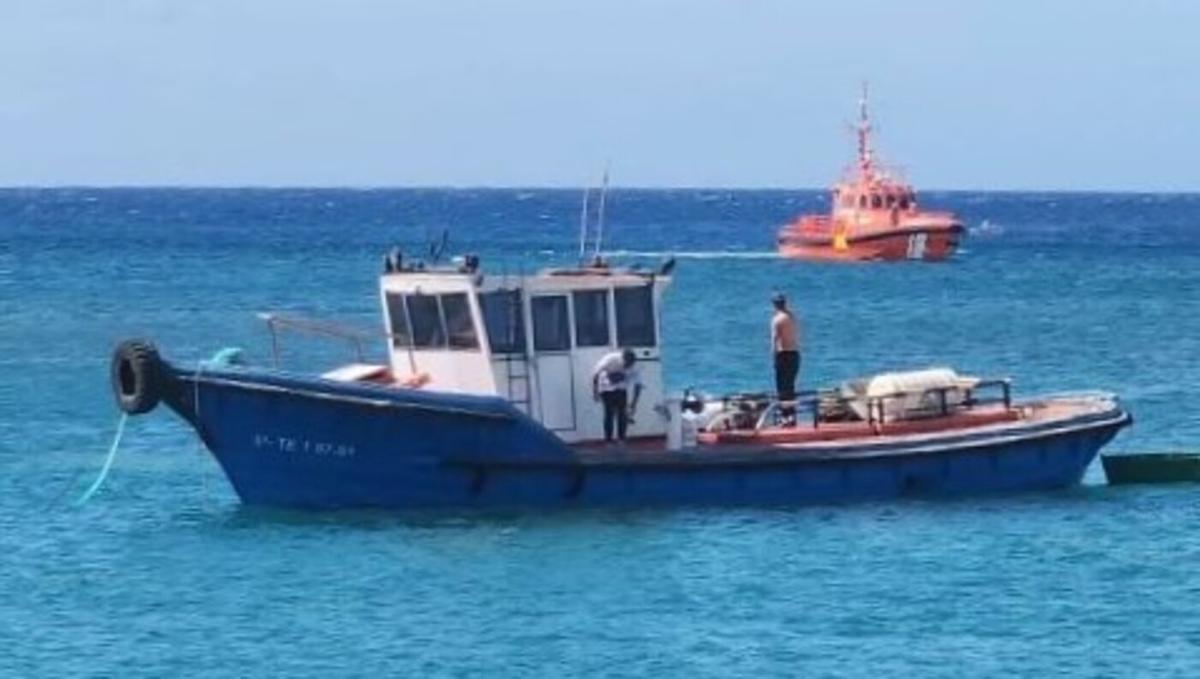 Tripulantes del pesquero achican el agua para evitar el hundimiento del mismo en presencia de una embarcación de Salvamento Marítimo
