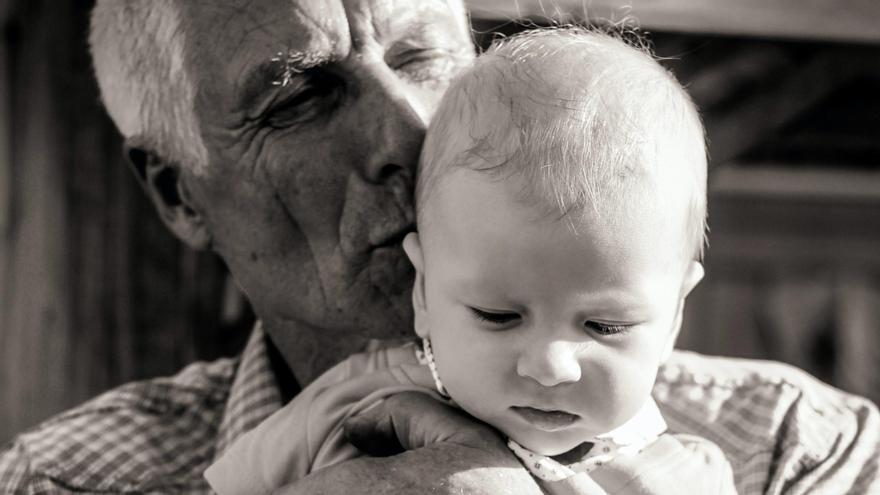 Una persona mayor y un bebé, con gran diferencia de edad, en una imagen de archivo.