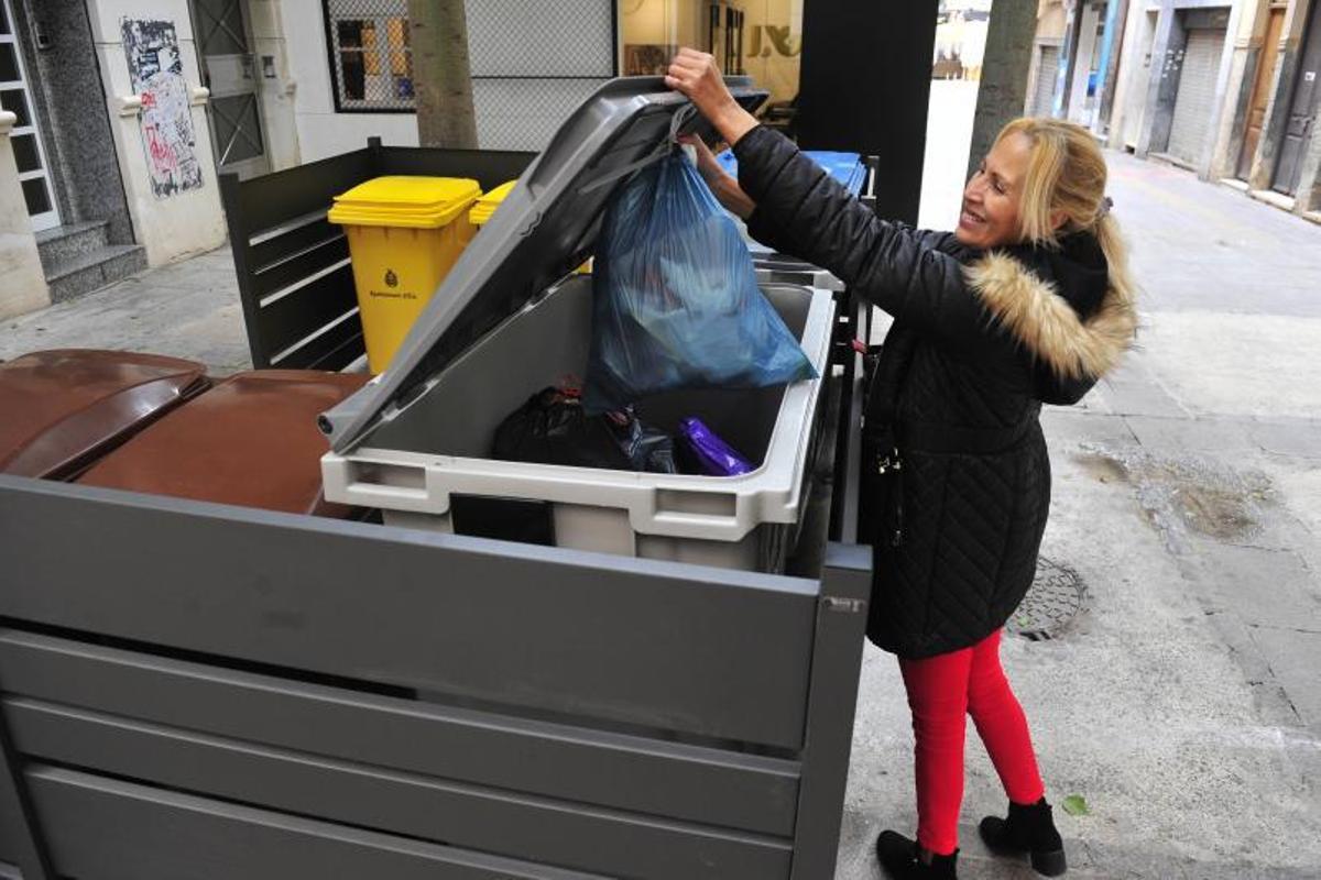 Una mujer tira la basura en un contenedor del centro de Elche