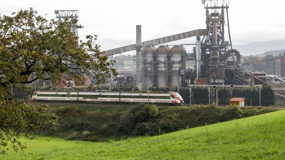 Un tren pasa ante los hornos altos de la factoría de ArcelorMittal en Gijón. | MARCOS LEóN