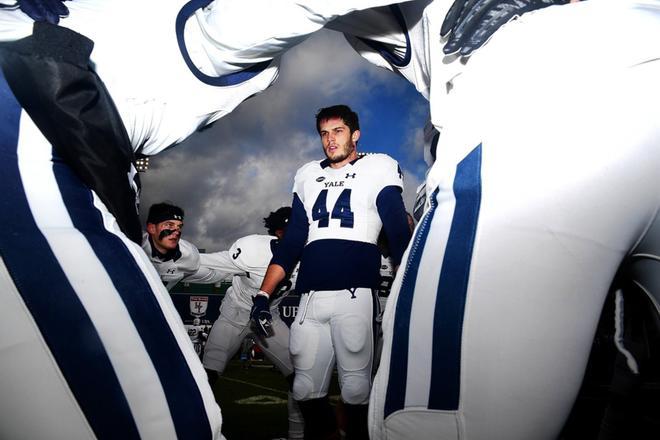 Scott Patton # 44 de Yale Bulldogs habla con sus compañeros de equipo en el grupo antes de un partido contra Harvard Crimson en Fenway Park