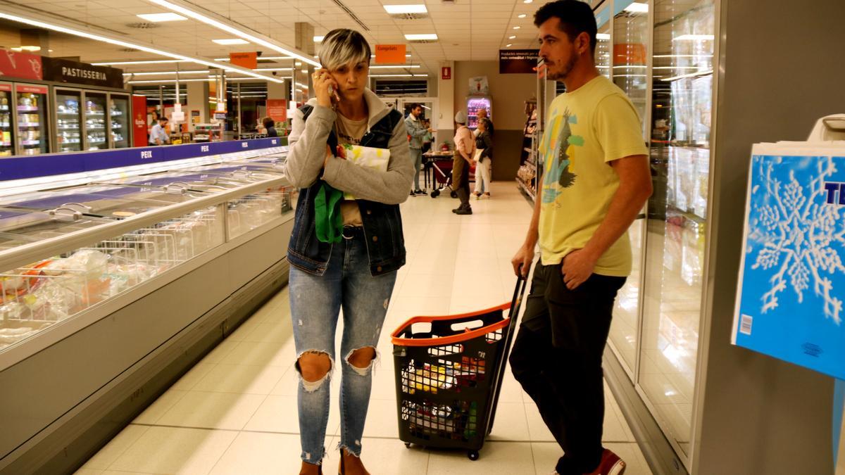 Una dona parla per telèfon mentre espera amb la seva parella dins del supermercat que acabi el confinament durant el simulacre d&#039;accident químic