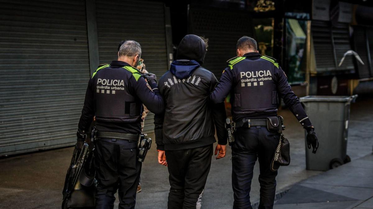 Dos agentes de la Guardia Urbana con un detenido