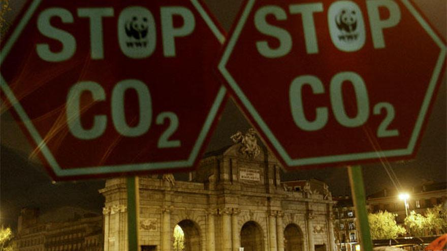 Manifestantes portan letreros contra la emisión de CO2 en un acto simbólico en Madrid.