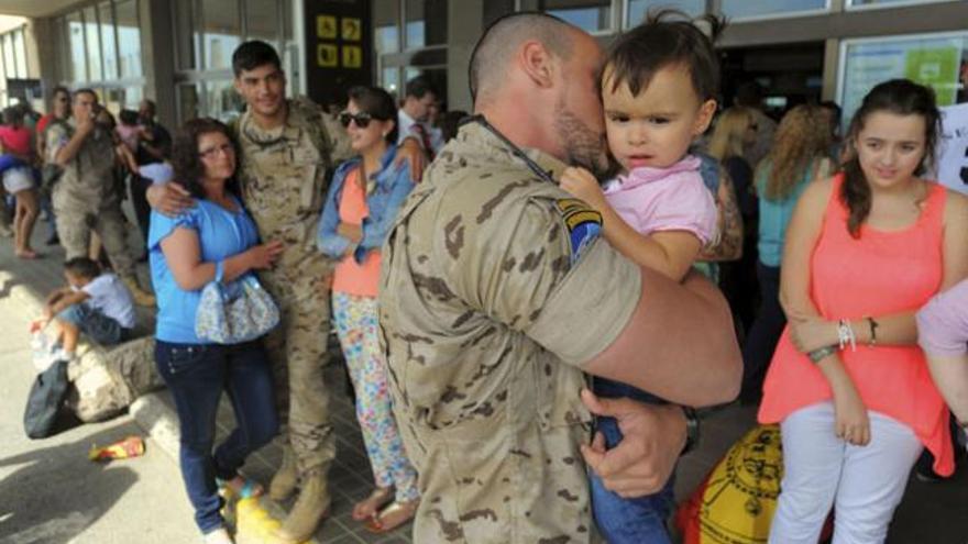 Un militar abraza a su hija en la terminal de salidas interinsulares antes de embargar al país afgano. | andrés cruz