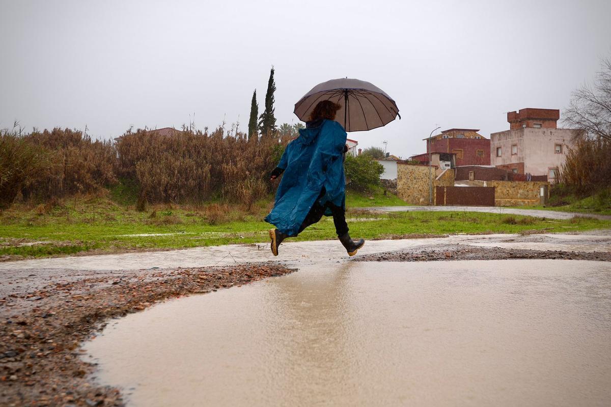 Una vecina de Alcolea supera una zona anegada por el agua caída con la borrasca Leonardo,