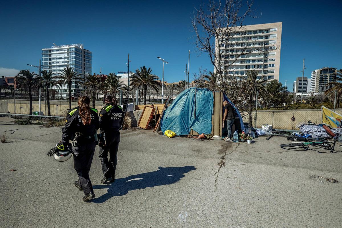 Dos agentes de la Guardia Urbana en el campamento que ha crecido enfrente de la playa de la Nova Mar Bella, en Barcelona.