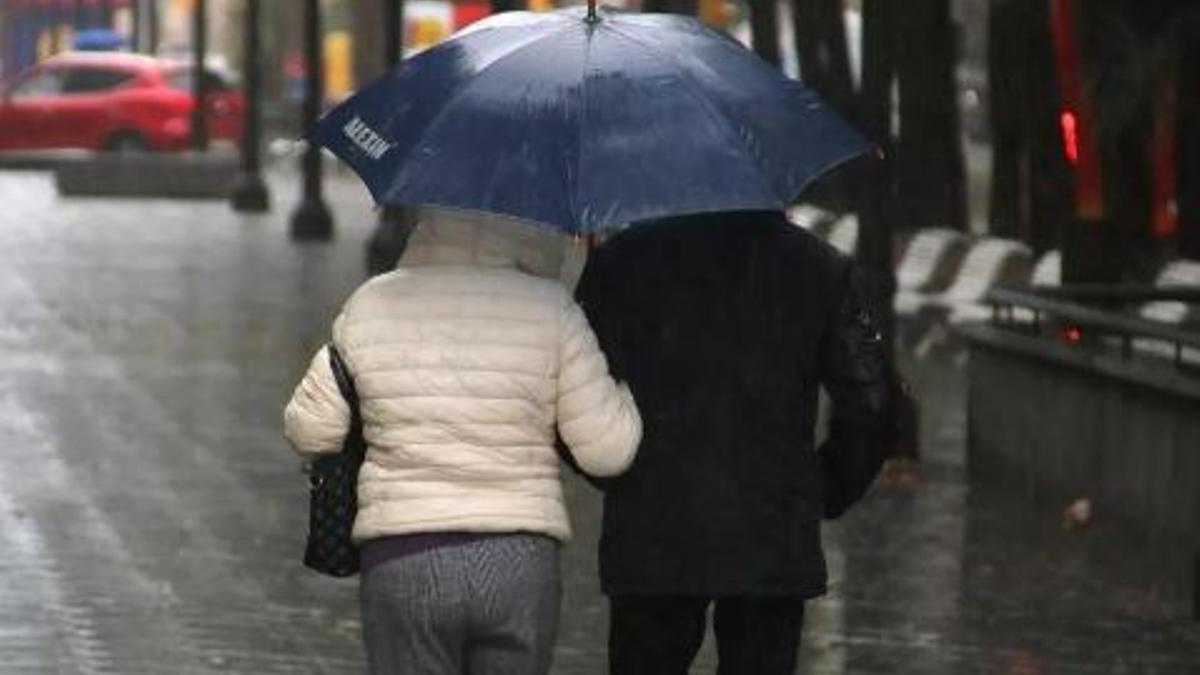 Una parella comparteix un paraigua durant un episodi de pluja