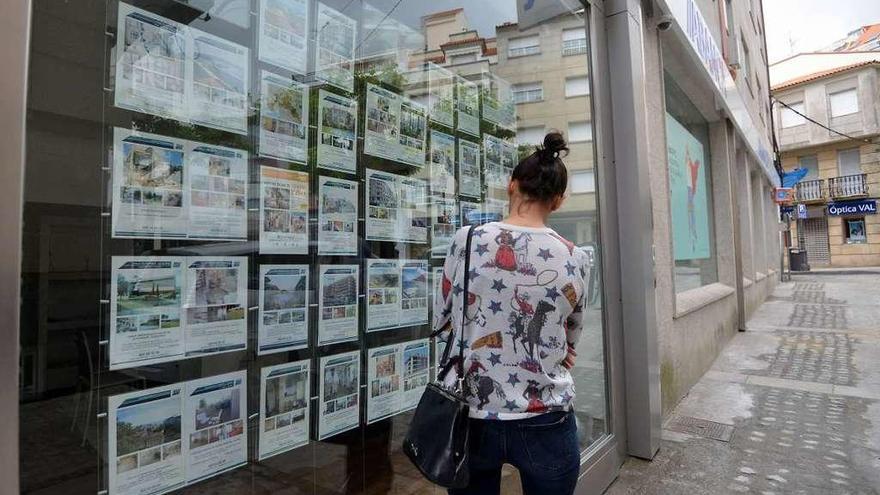 Una joven mira los anuncios de pisos turísticos en una inmobiliaria.