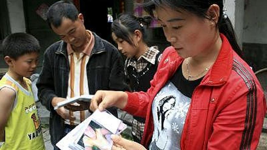 Peng Mingyan, madre de Li Xu, muestra las fotografías de su hija que tenía 15 años y asistía a clase en la escuela media de Juyuan, cerca de la ciudad de Dujiangyang (Sichuan, suroeste), donde quedaron sepultados alrededor de 900 niños tras el terremoto que sacudió China el pasado 12 de mayo.