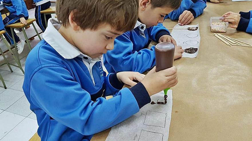 Dos pequeños, el curso pasado, con su uniforme escolar realizando una actividad creativa.