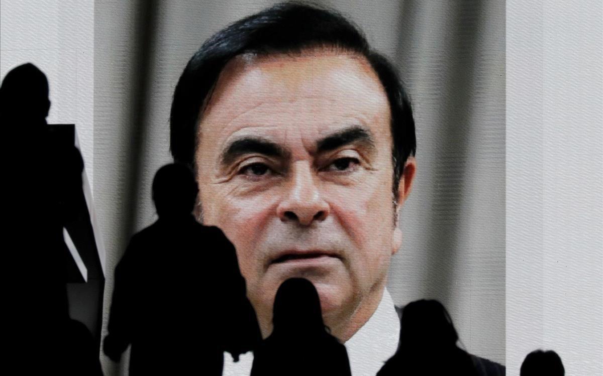 Peatones observan una pantalla que muestra una pieza informativa sobre el expresidente de Nissan Carlos Ghosn con motivo de su primera comparecencia ante el juez en Tokio, Japón.