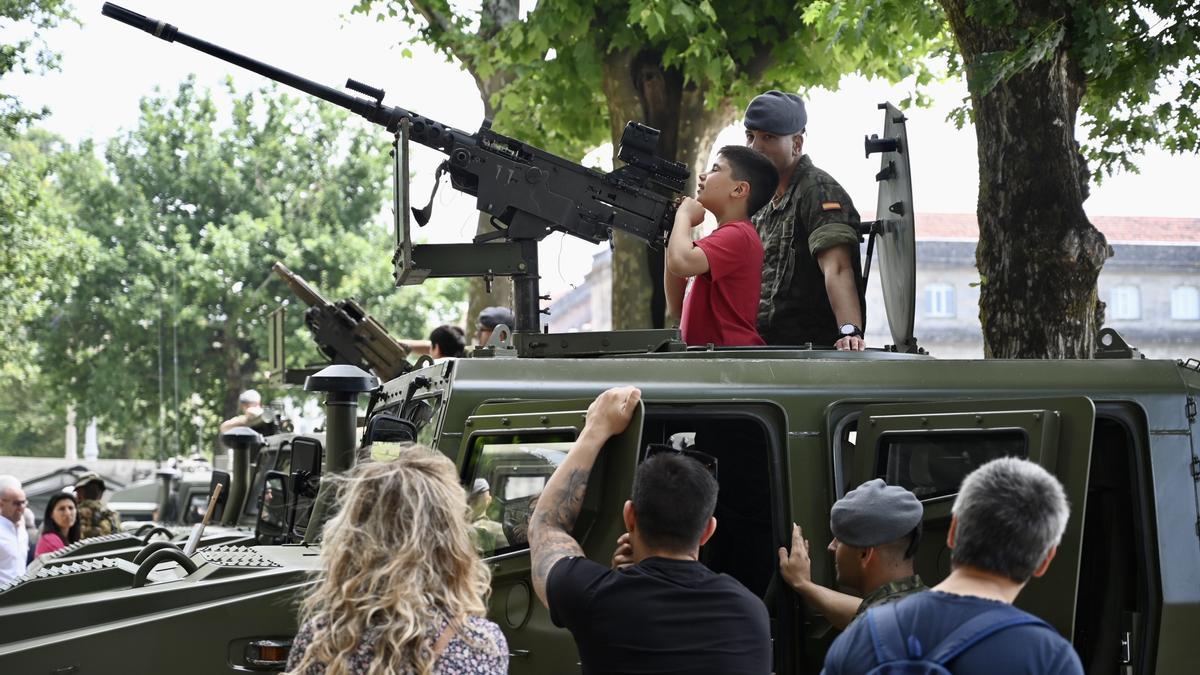 Un niño se pone en la perspectiva de disparo desde un vehículo blindado con ayuda de un soldado.