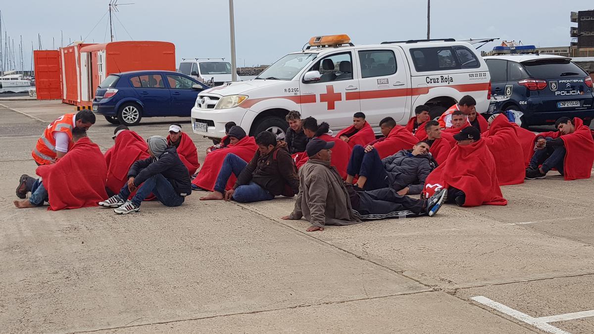 Inmigrantes llegados en patera a Lanzarote junto a un vehículo de Cruz Roja en Puerto Naos, en Arrecife.