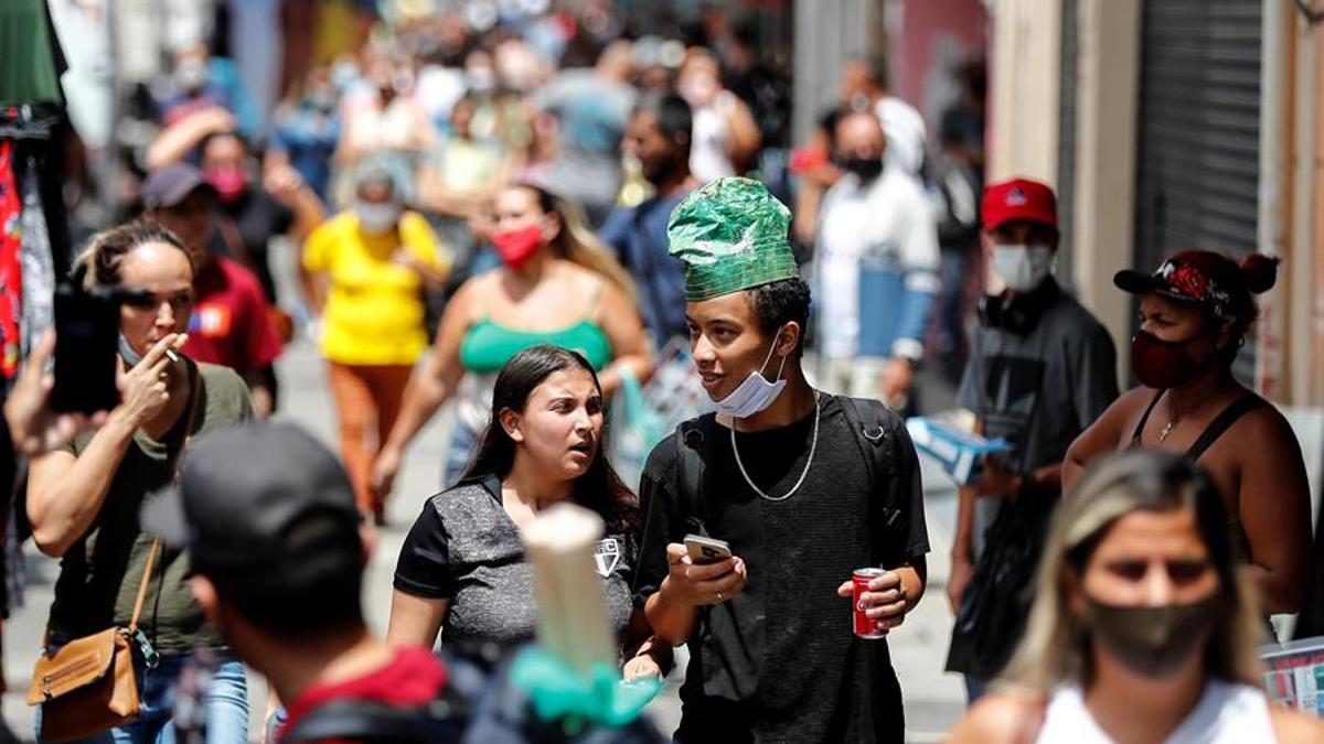 Dos jóvenes usando mal la mascarilla en Brasil