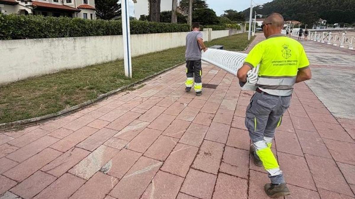 Operarios municipales trasladan un aparcabicis en el paseo de la playa de Santa Marina.