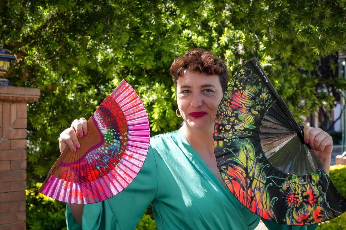 La artista Candelas Villa posa con dos de sus abanicos pintados a mano.