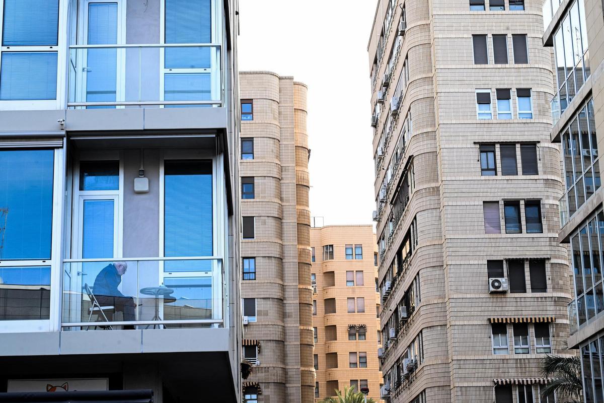 Una persona mayor en el balcón de su vivienda.