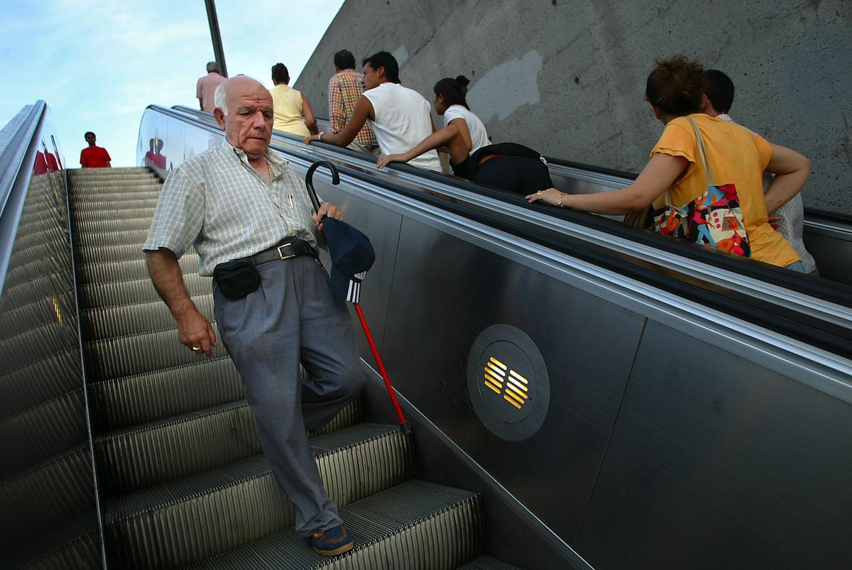 Un hombre baja por unas escaleras mecánicas estropeadas, en Montjuïc