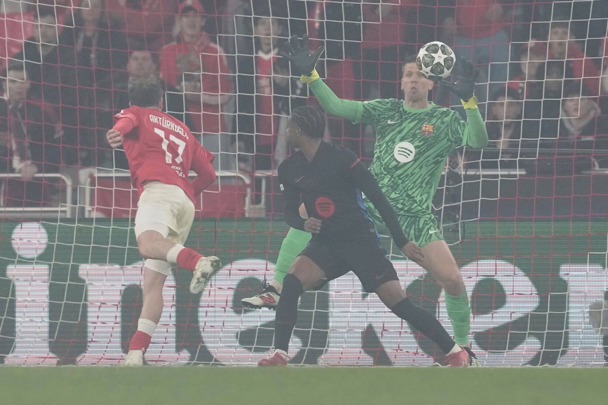 Barcelona's goalkeeper Wojciech Szczesny, right, saves against Benfica's Kerem Akturkoglu, left, during the Champions League round of 16 first leg soccer match between SL Benfica and FC Barcelona at the Luz stadium in Lisbon, Wednesday, March 5, 2025. (AP Photo/Armando Franca)