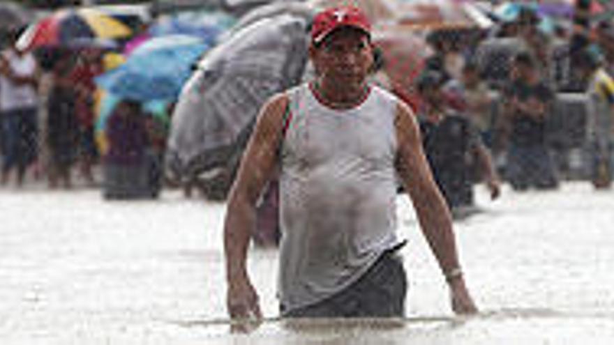 Un hombre camina el pasado domingo entre la inundación cen El Cubulero (Honduras)