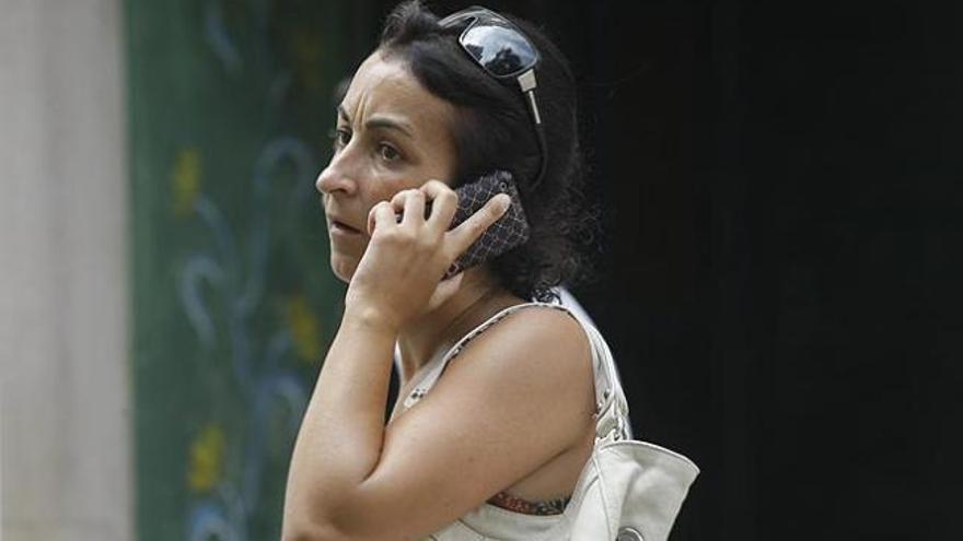 Una mujer haba por su teléfono móvil.