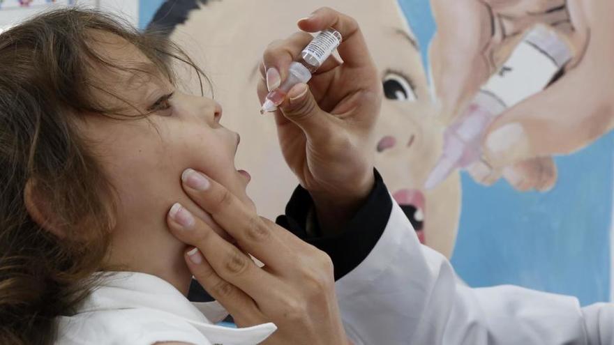 Una trabajadora sanitaria da una dosis de la vacuna contra la polio a una niña en Yemen.