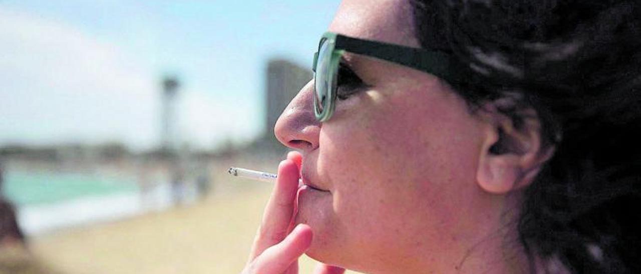 Una mujer fuma un cigarrillo cerca de una playa.   | // FERRAN NADEU