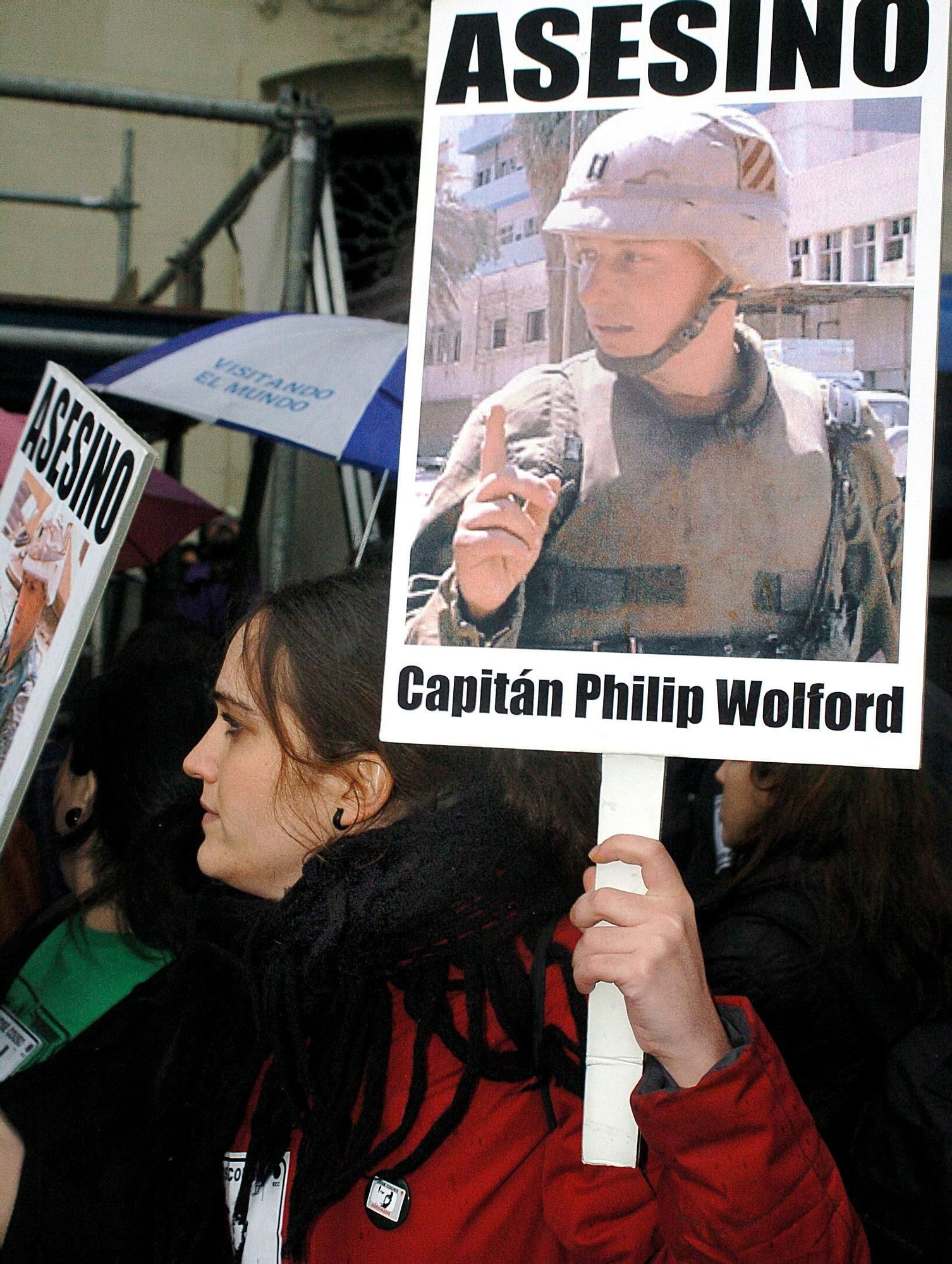 una manifestante porta un cartel con la foto de uno de los implicados en el ataque