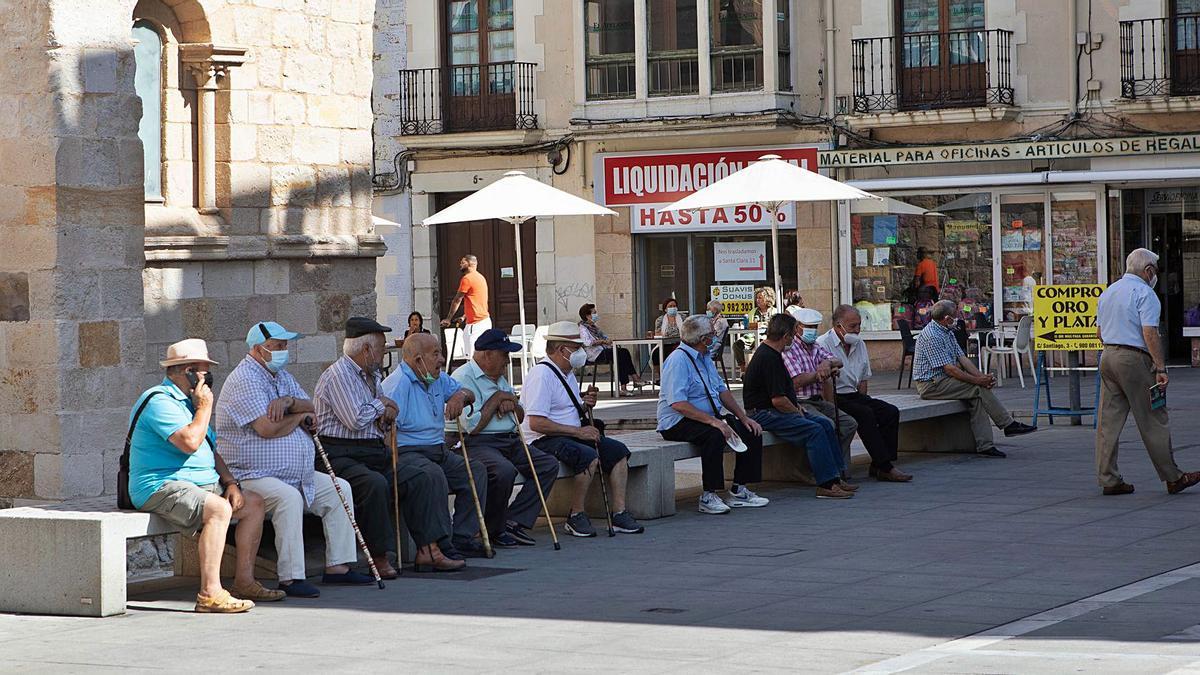 Un grupo de personas mayores descansa junto a la iglesia de Santiago del Burgo, en la calle Santa Clara.