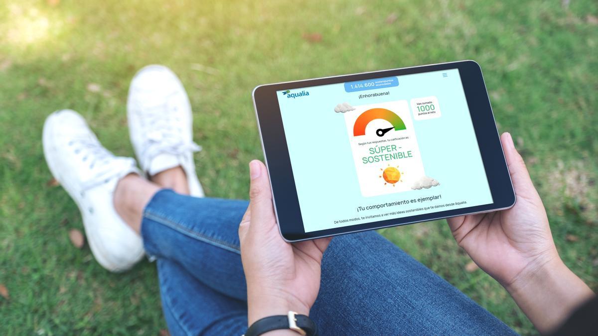 Mockup image of a woman holding and using black tablet pc with blank white desktop screen horizontally while sitting in the outdoors