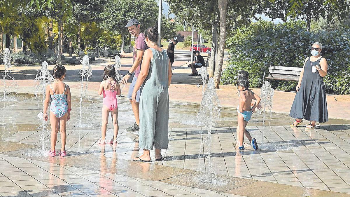 Unos niños se refrescan en la fuente del parque del Pont de Ferro de Castelló ante el sofocante calor.