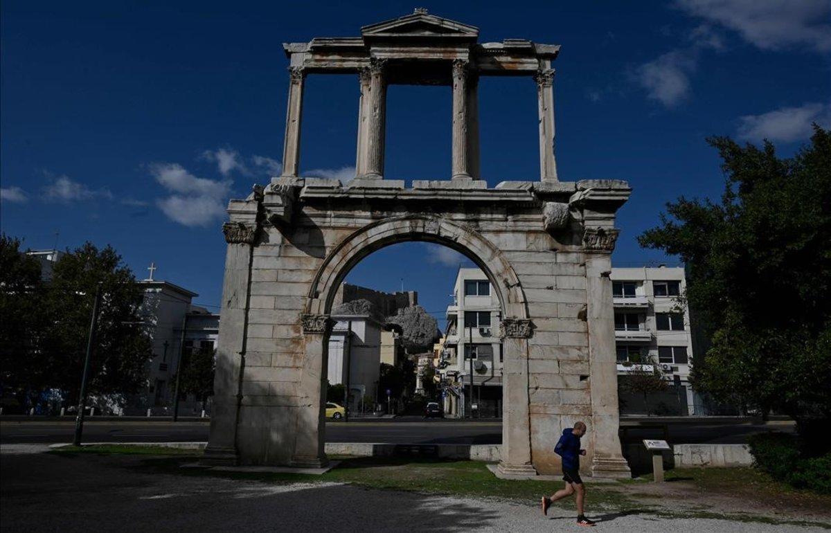 Un ’runner’ pasa frente a la Puerta de Adriano, en el centro de Atenas.