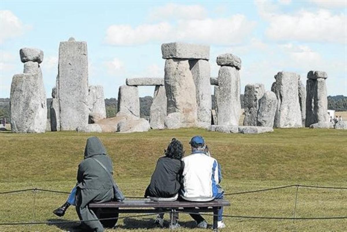 Uns turistes contemplen el monument megalític circular de Stonehenge.