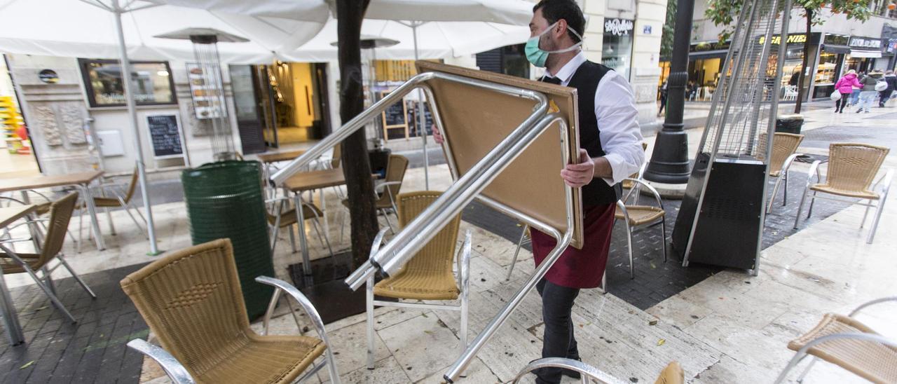 Un camarero recoge la terraza antes del cierre hostelero. | EDUARDO RIPOLL