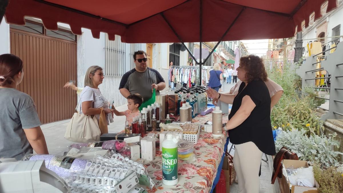 Varias personas se interesan por algunos de los productos de un puesto del mercado.