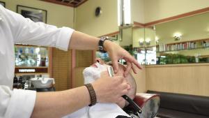 Un barbero afeitando a un cliente.