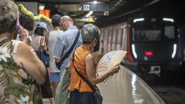 Una dona es venta mentre un tren entra a l’estació de metro de la plaça de Catalunya, a Barcelona. | MANU MITRU
