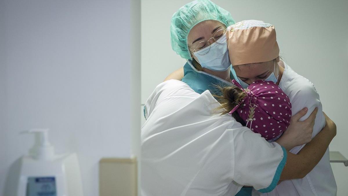Tres enfermeras se abrazan tras el traslado a planta de un paciente de la UCI.