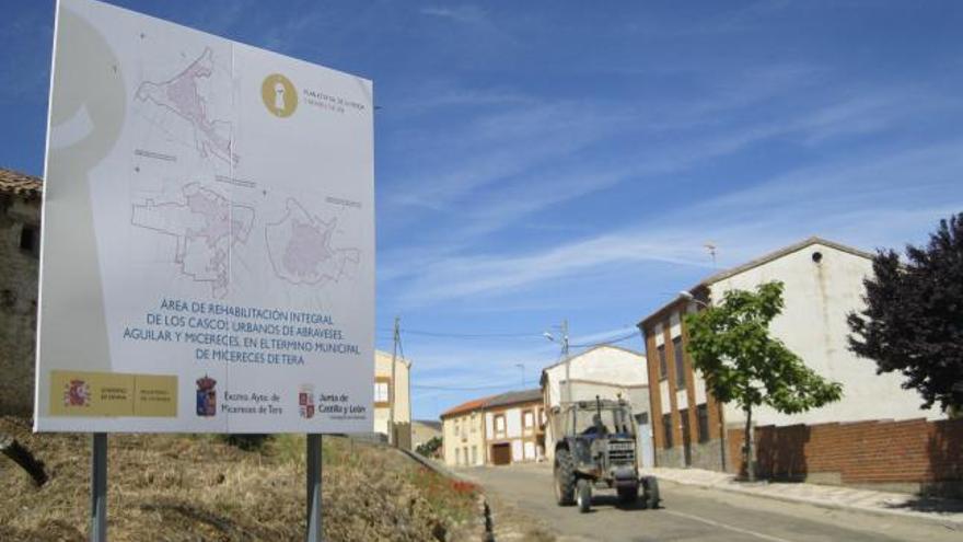 Un agricultor de Micereces conduce su tractor junto al cartel del ARI instalado a la entrada de la localidad.