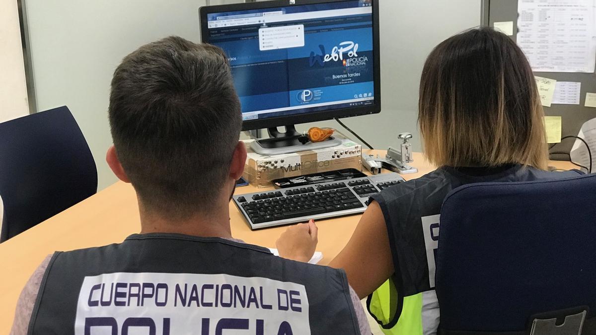 Archivo - Agentes de la Policía Nacional delante de un ordenador