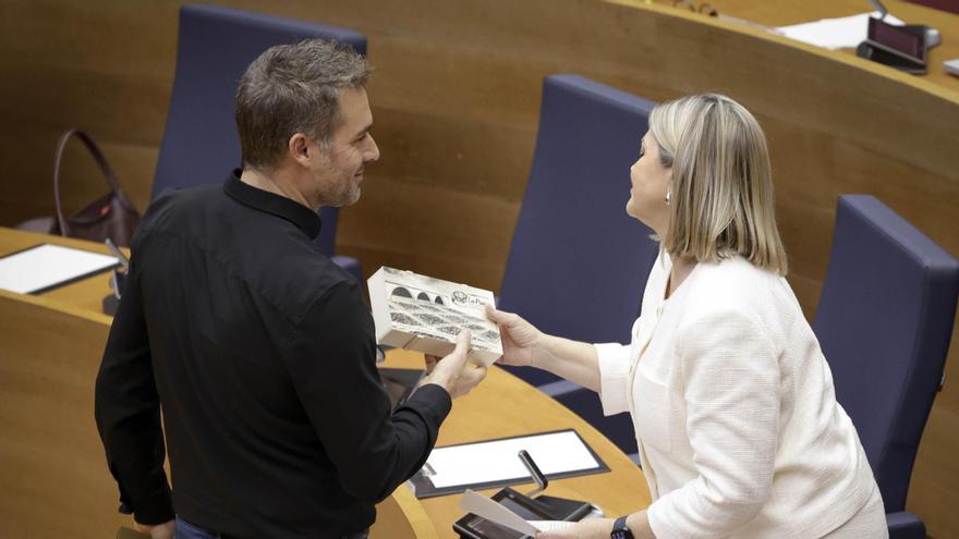 Gerard Fullana entrega a la consellera Ortí una caja de pasas en las Corts, este viernes.