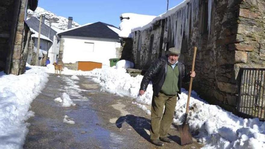 El vecino de Barjacoba Juan Fernández maneja una pala para desalojar la nieve en una de las calles con edificios cargados de carámbanos.