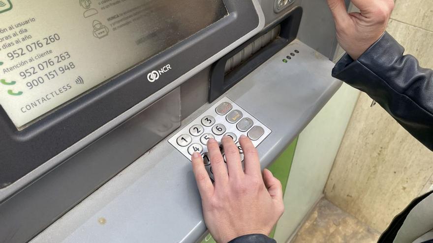 Una persona saca dinero de un cajero automático en una oficina bancaria en Málaga.