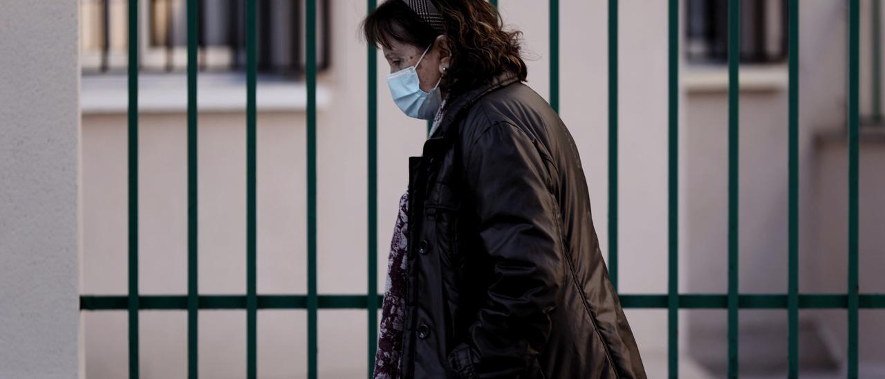 Una mujer camina con mascarilla.