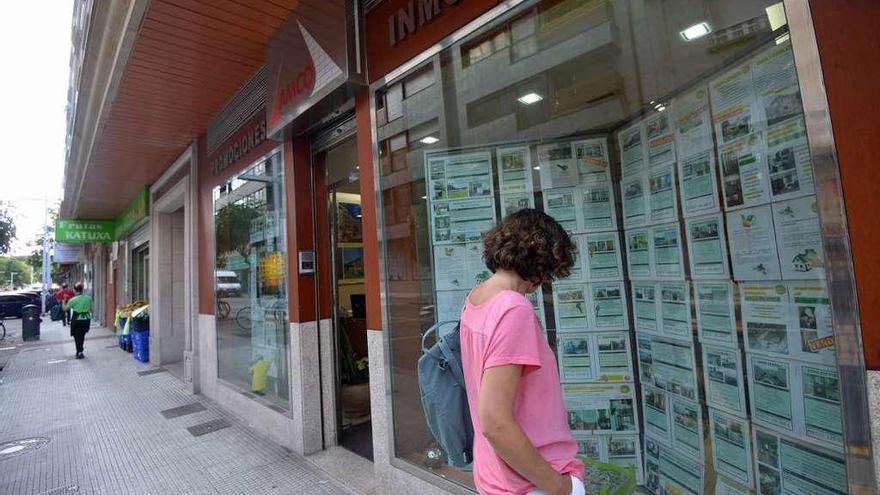 Una mujer observa los precios de los pisos en una inmobiliaria.