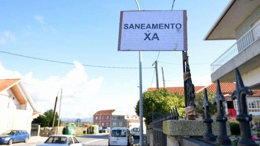 Un cartel instalado por los vecinos reclama el saneamiento al borde de la N-541 en Mourente. // G. Santos